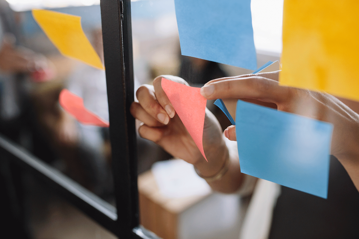 woman sticking adhesive notes on glass wall